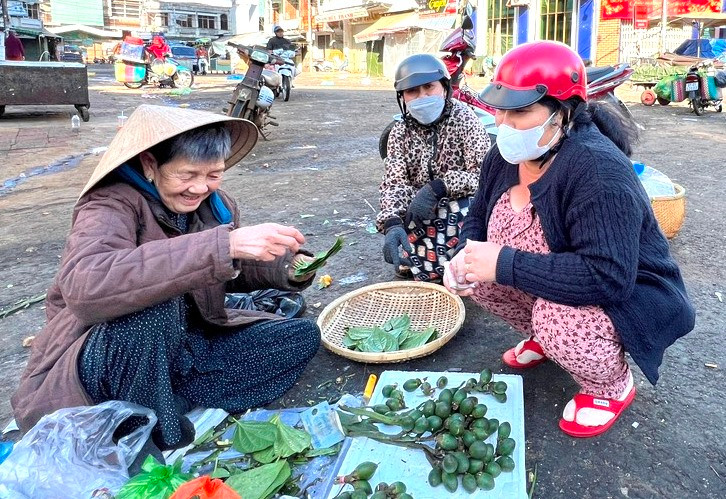 Mới hơn 6 giờ sáng mùng 2 Tết, bà Nguyễn Thị Hương (bìa trái, 90 tuổi ở 46 Trần Quý Cáp, TP. Pleiku) mang muối, trầu, cau ra trước cổng Trung tâm thương mại Pleiku bày bán để cầu may. Ảnh: Đinh Yến