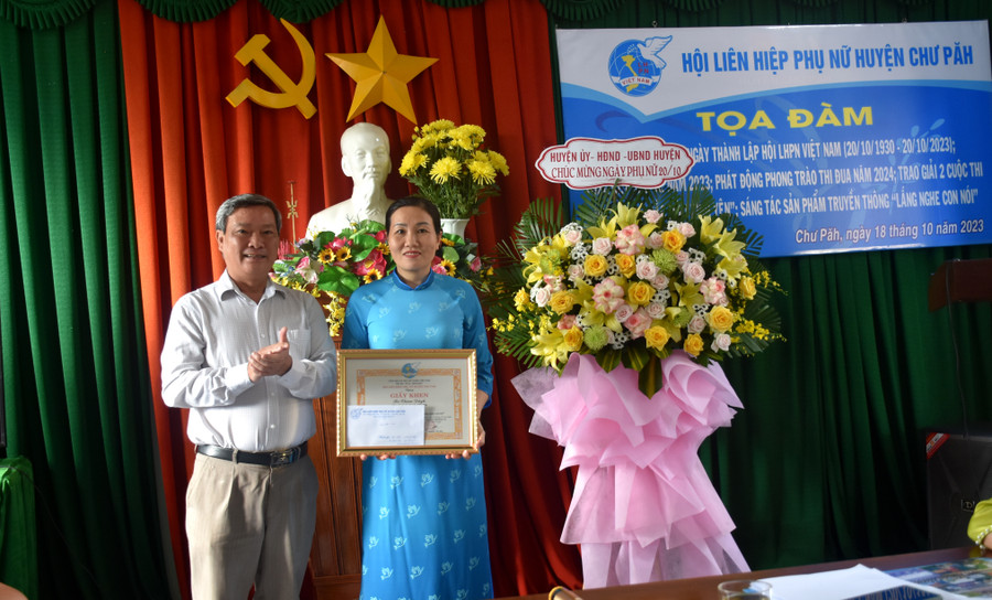 Ông Nguyễn Ngọc Thanh (bìa trái)-Phó Chủ tịch UBND huyện Chư Păh trao giải nhì cuộc thi sáng tác sản phẩm truyền thông &quot;Lắng nghe con nói&quot; cho chị Nguyễn Thanh Bình-Câu lạc bộ Thủ lĩnh của sự thay đổi Trường Tiểu học-THCS số 1 Chư Đang Ya. Ảnh: Đinh Yến