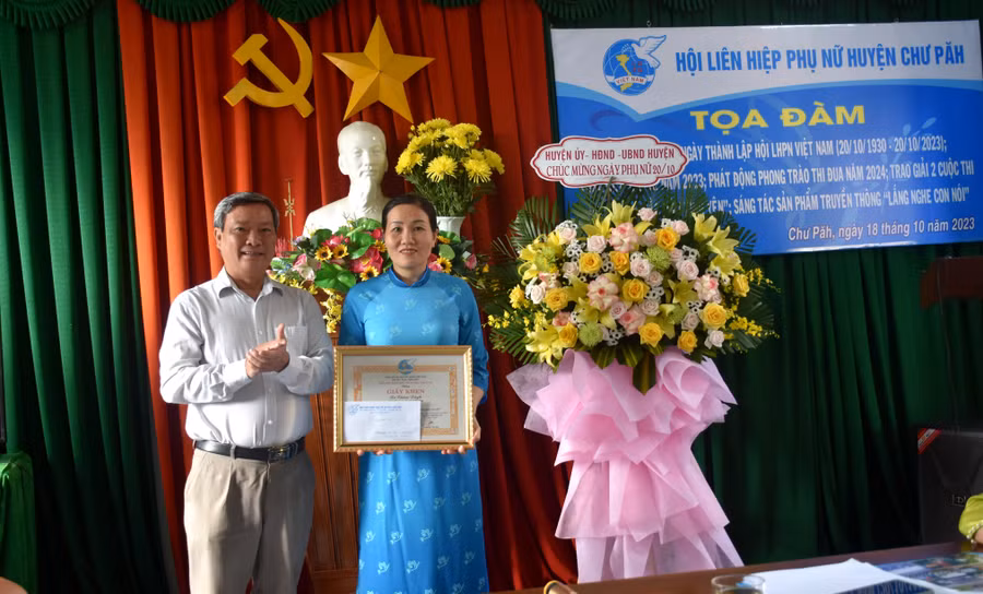 Ông Nguyễn Ngọc Thanh (bìa trái)-Phó Chủ tịch UBND huyện Chư Păh trao giải nhì cuộc thi sáng tác sản phẩm truyền thông "Lắng nghe con nói" cho chị Nguyễn Thanh Bình-Câu lạc bộ Thủ lĩnh của sự thay đổi Trường Tiểu học-THCS số 1 Chư Đang Ya. Ảnh: Đinh Yến