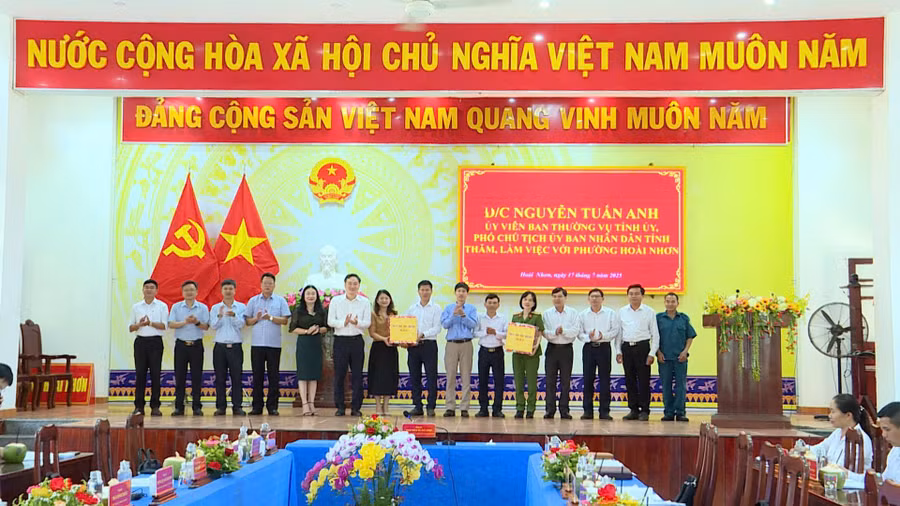 Phó Chủ tịch UBND tỉnh Nguyễn Tuấn Anh (thứ 6 từ trái sang) tặng quà cho lãnh đạo phường Hoài Nhơn. Ảnh: Phi Long