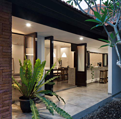 Phần hiên nhà mát mẻ, sạch sẽ, được chủ nhân tạo điểm nhấn bằng những chậu cây cảnh to. Để giải quyết vấn đề thiếu ánh sáng ban ngày, kiến trúc sư tạo một khu vườn nho nhỏ bên cạnh ngôi nhà như một đường hầm gió và ánh sáng. 