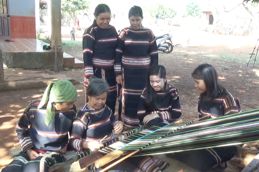Bà Blup truyền dạy nghề dệt thổ cẩm cho các bạn trẻ. Ảnh : N.T