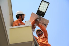 Các nhân viên Công ty Điện lực Gia Lai lắp đèn điện cho công trình “Thắp sáng đường quê” cho buôn Ngôl. Ảnh: Hoàng Hoài