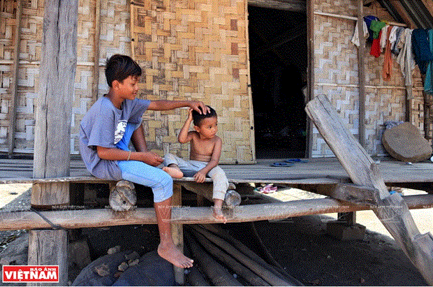 Cậu bé M’nông hết giờ học trông em cho bố mẹ đi rẫy.