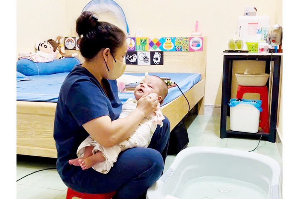 Chị Hnơr (nhân viên Newborn Care Spa) tắm cho bé trong phòng kín gió, thao tác nhẹ nhàng và thư giãn. Ảnh: H.H 11hh.jpg