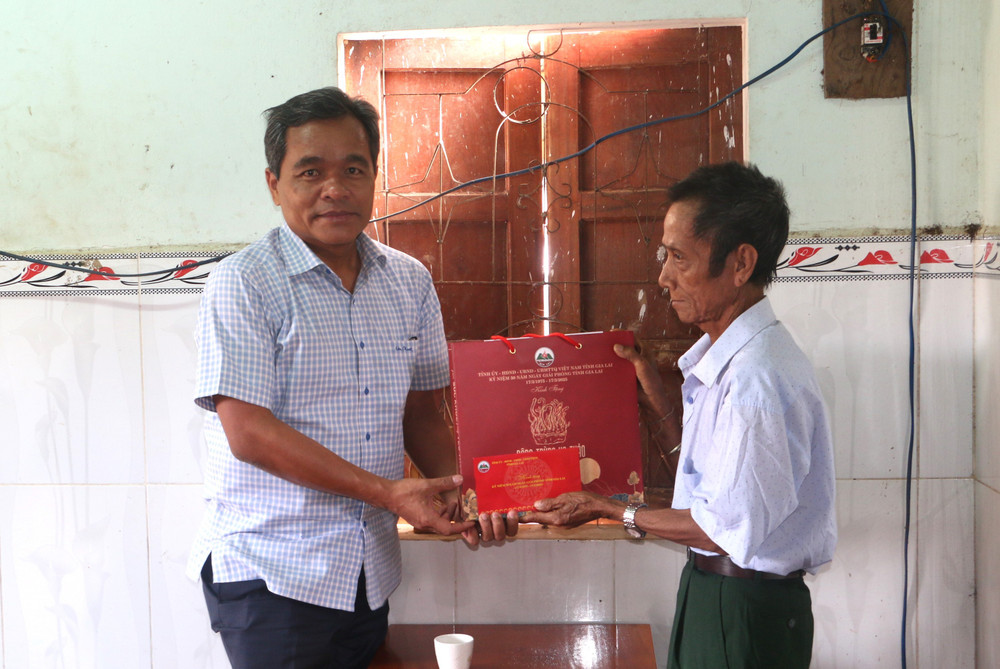 Bí thư Tỉnh ủy Hồ Văn Niên tặng quà ông Đinh Anhuy (làng Chợch, xã Lơ Ku)-người hoạt động kháng chiến nhiễm chất độc hóa học. Ảnh: Q.T img-8399.jpg