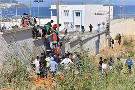 Người di cư trèo qua hàng rào biên giới để vào vùng lãnh thổ Ceuta của Tây Ban Nha từ thành phố Fnideq, Maroc. 