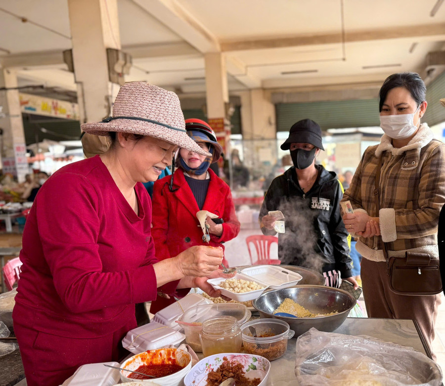 Ms. Trinh Thi Hoa (left) serves sticky rice to customers. Photo: TUE NGUYEN ba-trinh-thi-hoa-ben-trai-dang-lay-xoi-cho-khach-1.jpg