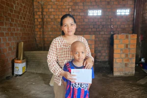 Chị Thơng (mẹ em Thạch) nhận tiền hỗ trợ do Báo Gia Lai và bạn đọc trao tặng. Ảnh: Ngọc Duy