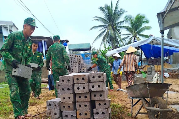 Cán bộ, chiến sĩ Đồn Biên phòng Tam Quan Nam hỗ trợ vận chuyển vật liệu xây nhà tình nghĩa cho gia đình thuyền viên Hà Quốc Phong. Ảnh: T.B