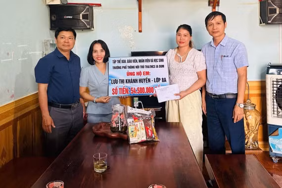 Đại diện Trường Phổ thông Nội trú Tiểu học và Trung học cơ sở Ia Dom trao tiền hỗ trợ gia đình em Lưu Thị Khánh Huyền. Ảnh: ĐVCC