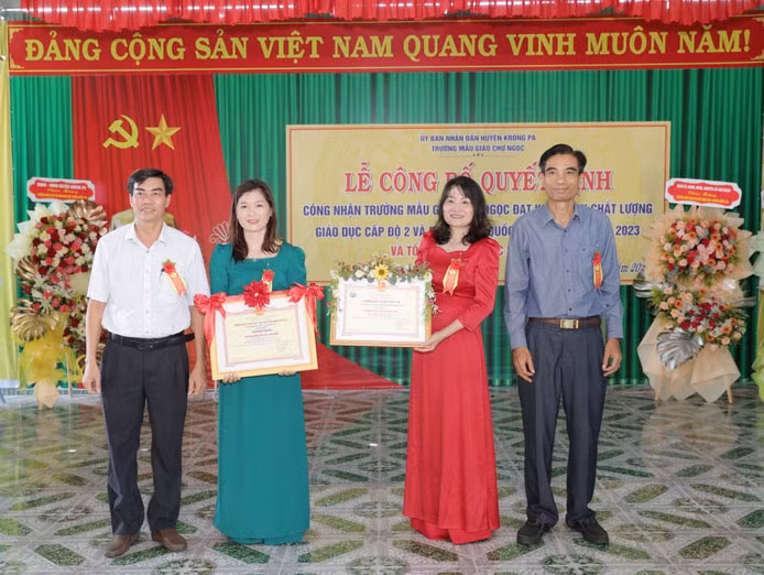 Phó Chủ tịch UBND huyện Krông Pa Ksor Tin (bìa phải) và Trưởng phòng Giáo dục và Đào tạo huyện Chu Sỹ Lin (bìa trái) trao bằng công nhận Trường đạt chuẩn quốc gia mức độ 1 và chứng nhận Trường đạt kiểm định chất lượng giáo dục cấp độ 2 cho Trường Mẫu giáo Chư Ngọc. Ảnh: Sơn Trung