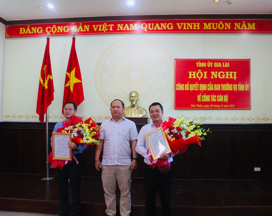Phó Bí thư Tỉnh ủy Rah Lan Chung (đứng giữa) trao quyết định và tặng hoa chúc mừng đồng chí Nguyễn Hoàng Phong (bìa trái) và Vũ Hồng Duy. Ảnh: Vũ Chi