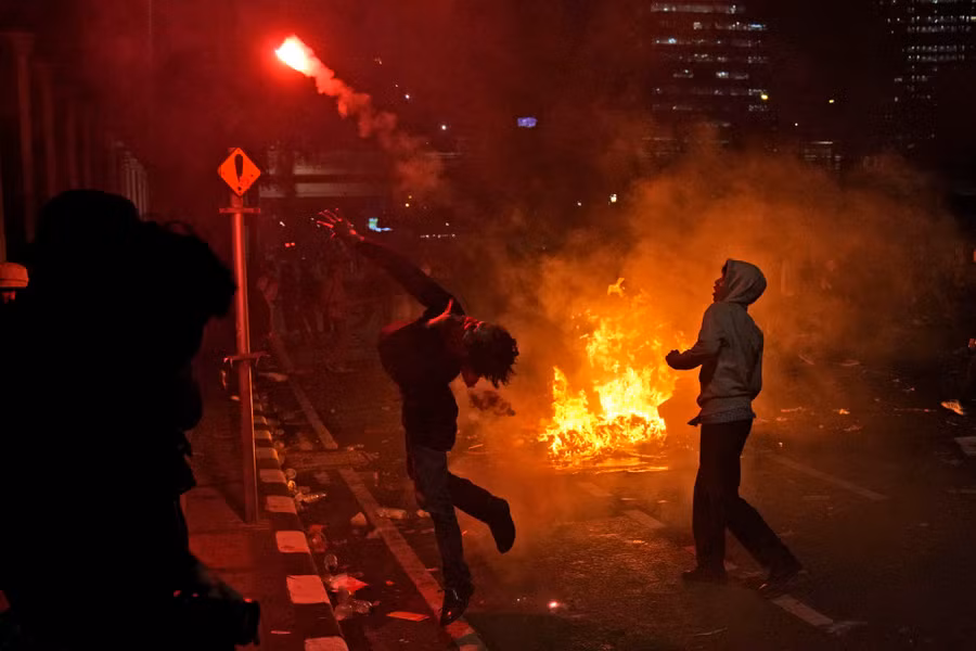 Người biểu tình đốt lửa tại Jakarta, tấn công cả cảnh sát hôm 22-8.Ảnh: AP