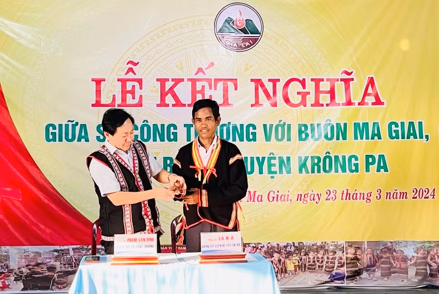 Đại diện lãnh đạo Sở Công thương và buôn Ma Giai trao cho nhau chiếc còng của người Jrai tượng trưng cho sự gắn kết giữa 2 đơn vị. Ảnh: Vũ Chi