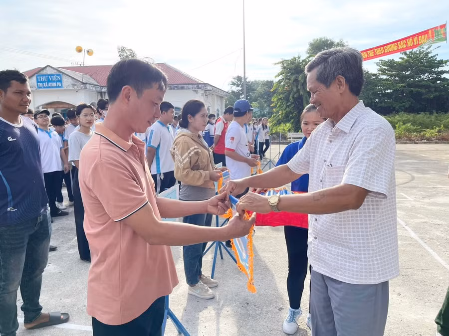 Ông Ksor Vinh-Phó Bí thư Thường trực Thị ủy (bìa phải) tặng cờ lưu niệm cho các đoàn vận động viên tham gia hội thi thể thao các dân tộc thiểu số. Ảnh: Vũ Chi