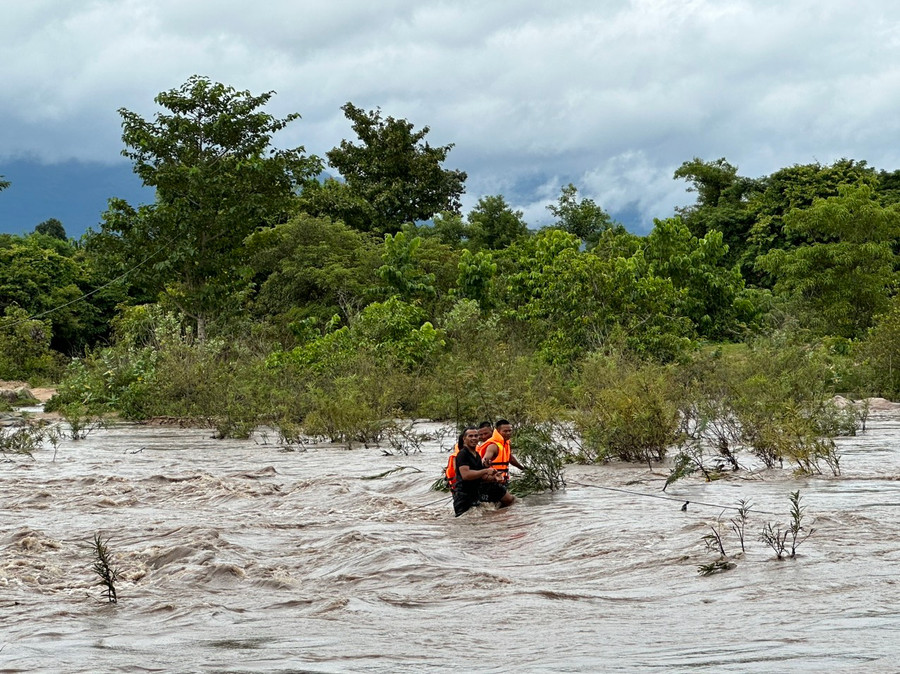 Lực lượng chức năng xã Ia Rsai phối hợp với người dân đưa 2 em nhỏ bị mắc kẹt giữa dòng nước lũ vào bờ an toàn. Ảnh: UBND xã cung cấp
