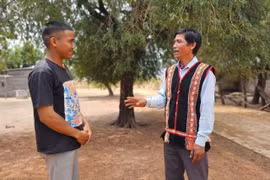 Ông Kpă Blon (bìa phải) trò chuyện với thanh niên trong làng về việc đảm bảo an ninh trật tự.Ảnh: R.H