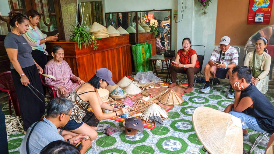 Trải nghiệm duỗi lá làm nón mang lại cảm xúc thú vị cho du khách. Ảnh: Ngọc Nhuận dscf2547.jpg