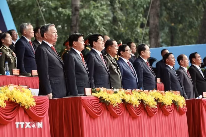 Các đồng chí lãnh đạo Đảng, Nhà nước và khách quốc tế thực hiện nghi thức chào cờ. (Ảnh: TTXVN)