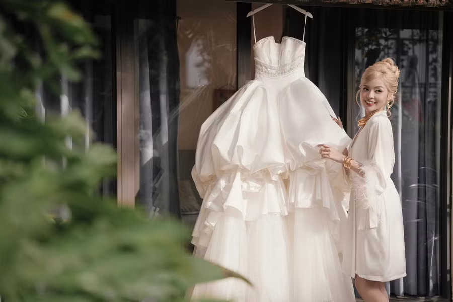 Cô chọn thiết kế tông màu trắng, được sử dụng chất liệu lụa mikado mềm mại, nhập khẩu từ Nhật Bản của nhà thiết kế Kim Anh. Điểm nhấn của chiếc váy là việc sử dụng pha lê swarovski và cườm thủy tinh để tạo được độ sáng, lấp lánh giúp cô dâu nổi bật hơn trong ngày trọng đại