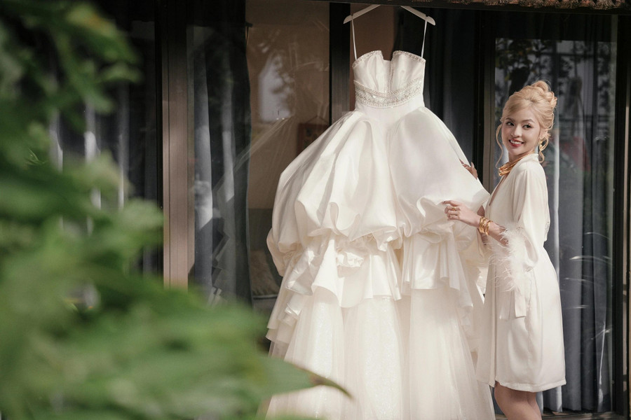 Cô chọn thiết kế tông màu trắng, được sử dụng chất liệu lụa mikado mềm mại, nhập khẩu từ Nhật Bản của nhà thiết kế Kim Anh. Điểm nhấn của chiếc váy là việc sử dụng pha lê swarovski và cườm thủy tinh để tạo được độ sáng, lấp lánh giúp cô dâu nổi bật hơn trong ngày trọng đại