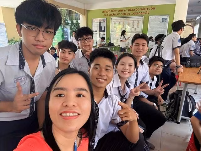 Chí Thanh ngồi kế cô giáo chủ nhiệm và các bạn trong lớp