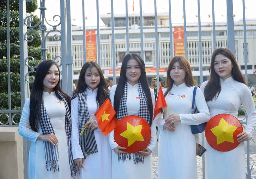 Các cô gái trong áo dài thướt tha, chụp ảnh trước Hội trường Thống Nhất