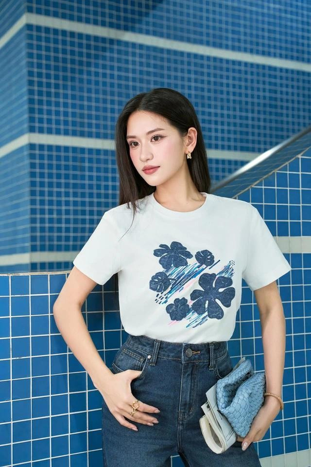 Áo phông trắng phối quần denim cạp cao tạo điểm nhấn nổi bật. Họa tiết hoa màu xanh denim làm nên hình ảnh tone sur tone đậm chất thời trang