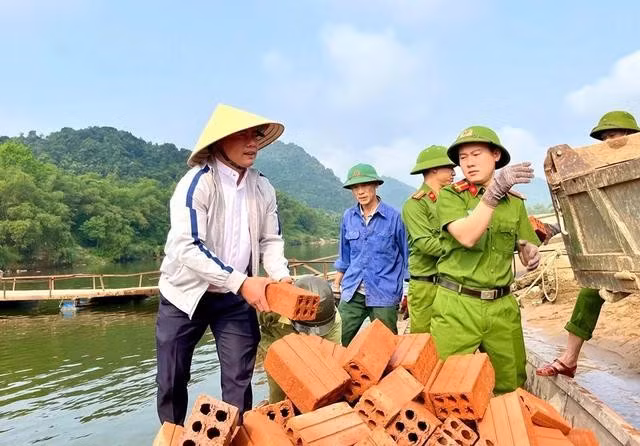 Lực lượng công an xã và linh mục Trương Văn Thực, giáo xứ Đồng Hội (xã Đồng Hóa, H.Tuyên Hóa, Quảng Bình) cùng tham gia vận chuyển vật liệu xây dựng giúp người dân xóa nhà tạm, nhà dột nát