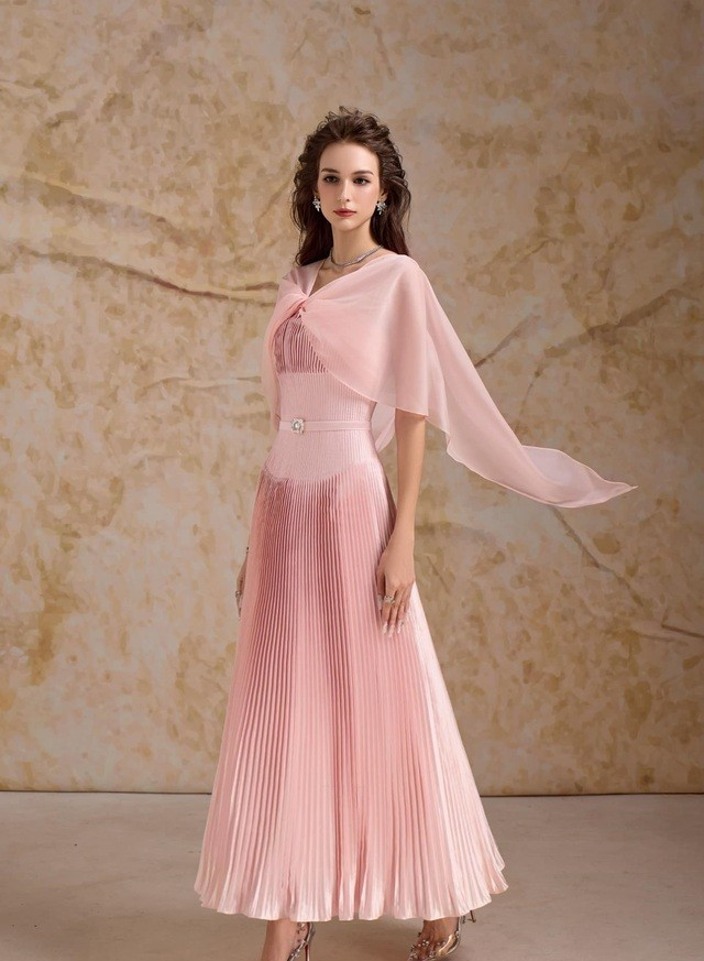 Câu chuyện của hoa hồng, của những tầng tulle, voan điệu đà xếp lớp và tông hồng coral sang trọng. Thân áo ôm sát tôn lên đường cong chuẩn mực, tạo nên sự tương phản tinh tế với tùng váy dập ly cầu kỳ