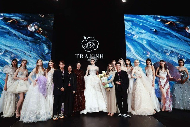Nhà thiết kế Trà Linh (ôm hoa) trong màn chào kết bộ sưu tập A Drop In The Ocean vừa trình diễn tại Sanya Bridal Fashion Week