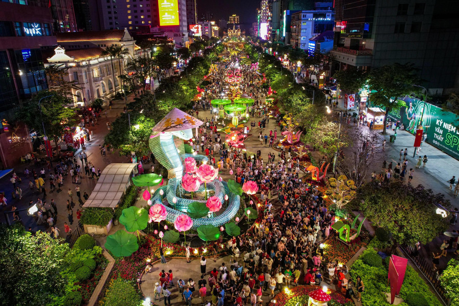 Nhiều người tham quan đường hoa đêm giao thừa trong lúc chờ ngắm pháo hoa bắn lên từ đầu đường hầm sông Sài Gòn (TP.Thủ Đức)