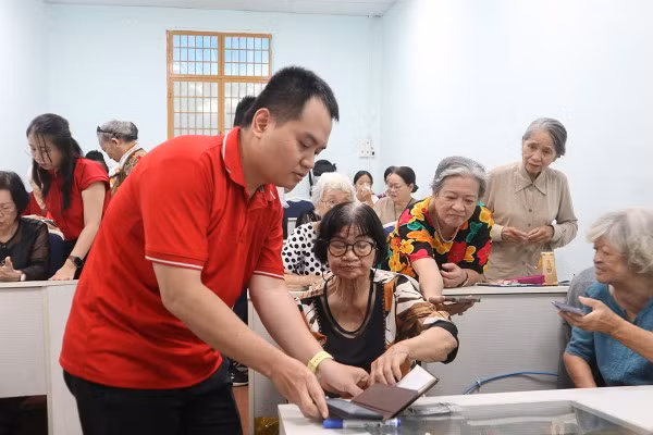 Anh Nguyễn Đăng Khoa hướng dẫn người lớn tuổi sử dụng ứng dụng mạng xã hội.