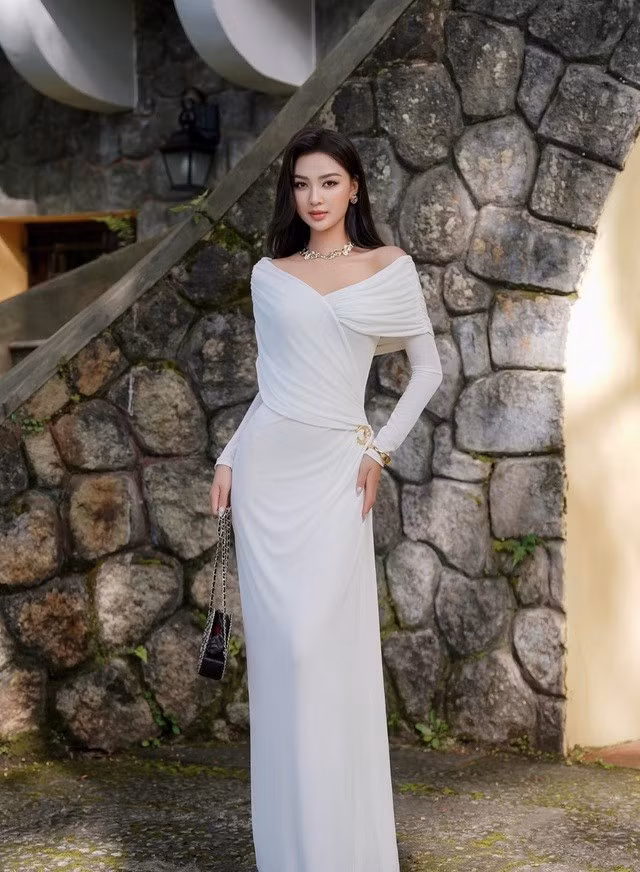 Thiết kế dáng dài được tạo nên từ những đường cắt mềm mại, ôm trọn từng đường nét quyến rũ mà duyên dáng. Cộng hưởng chi tiết trễ vai tựa cánh hoa vừa khẽ mở, để lại chút dư âm của sự e ấp nhưng vẫn kiêu hãnh, một vẻ đẹp khiến bao người muốn ngắm nhìn mãi