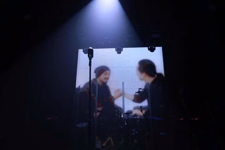 Nhạc sĩ Trần Lập xuất hiện trên màn hình với sự hỗ trợ của công nghệ, cùng các thành viên ban nhạc vui vẻ chuyện trò.