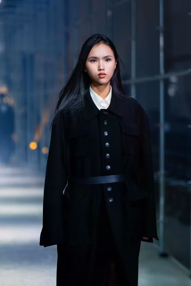 Khi trình diễn cho nhà mốt Slingtone, nàng mẫu Việt thể hiện bộ trang phục gồm măng tô đen phối sơ mi trắng và thắt lưng to bản