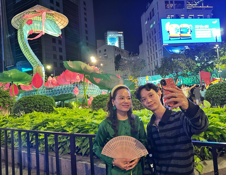 Chị Ngọc Thảo (40 tuổi) và anh Tấn Thông (33 tuổi) đi từ Q.4 đến Q.1 để tham quan đường hoa đêm giao thừa. &quot;Lát tôi còn về nhà cúng giao thừa, nên đến đây chủ yếu để tham quan đường hoa. Năm nay, linh vật rắn đẹp quá luôn, hoa đẹp nhưng ấn tượng nhất với tôi là tạo hình rắn dễ thương&quot;, chị chia sẻ