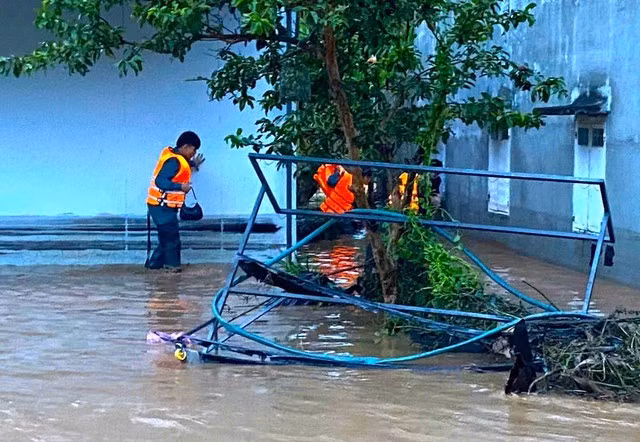 Lực lượng chức năng tiếp cận các ngôi nhà bị nước bao vây để giúp đỡ người dân.