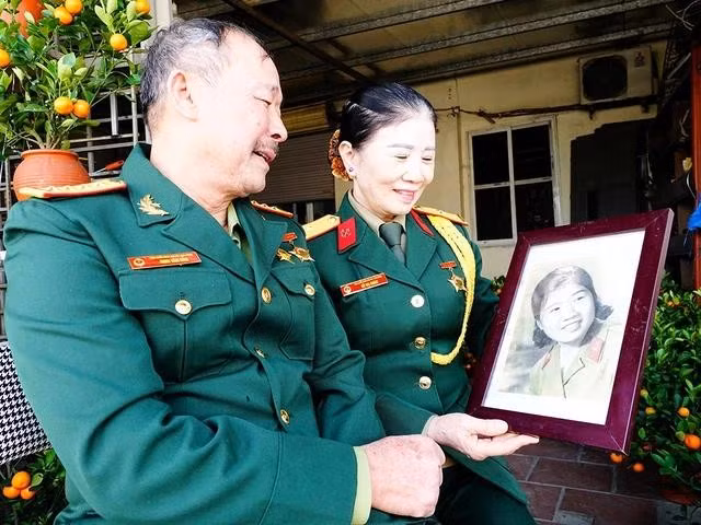 Ông Bản và bà Châm bên tấm hình bà Châm hồi mới nhập ngũ