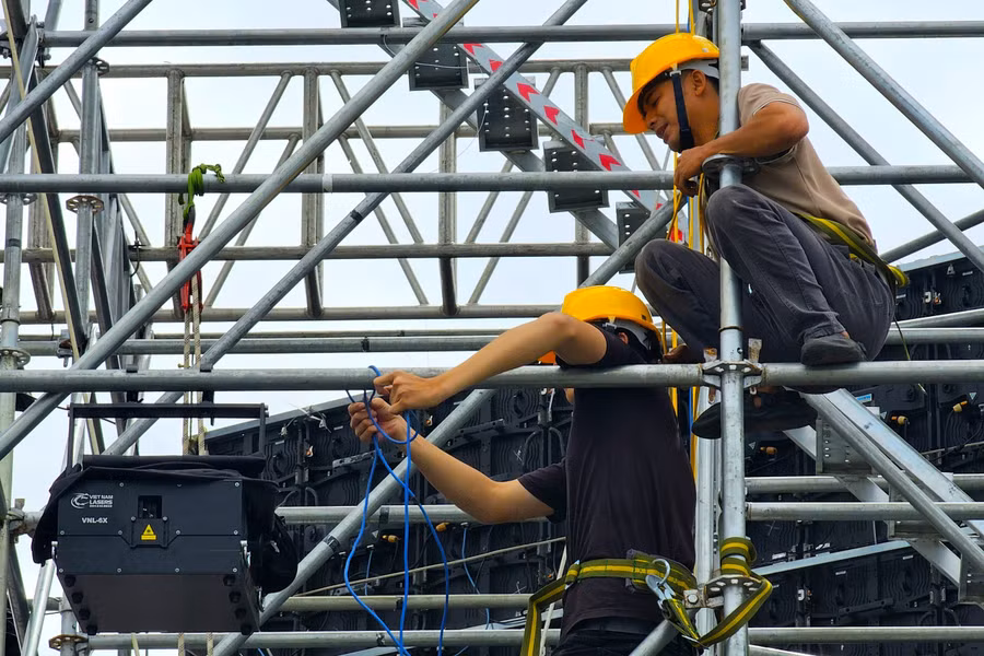 Các kỹ sư, công nhân gấp rút lắp đặt thiết bị sân khấu chính của lễ khai mạc. Sân khấu chính lấy ý tưởng từ hoa dã quỳ làm chủ đạo với nhiều nghệ sĩ nổi tiếng biểu diễn.