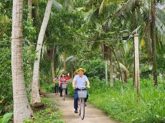 Du khách thích thú đạp xe dưới những tán dừa