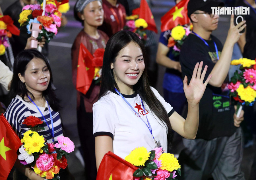 Hoa hậu quốc tế 2024 Huỳnh Thị Thanh Thủy tươi cười vẫy tay chào người dân khi đi qua khán đài trên đường Lê Duẩn