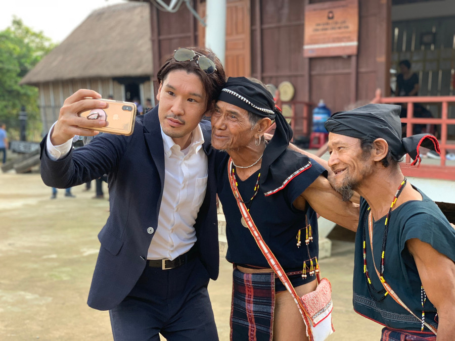 Den eldste i landsbyen Hmưnh (helt til høyre) gir besøkende alltid dype historier om Bahnar-tro og -skikker. Foto: Minh Chau du-khach-chup-anh-cung-cac-gia-lang-o-lang-du-lich-cong-dong-mo-hra-dapjpg.jpg