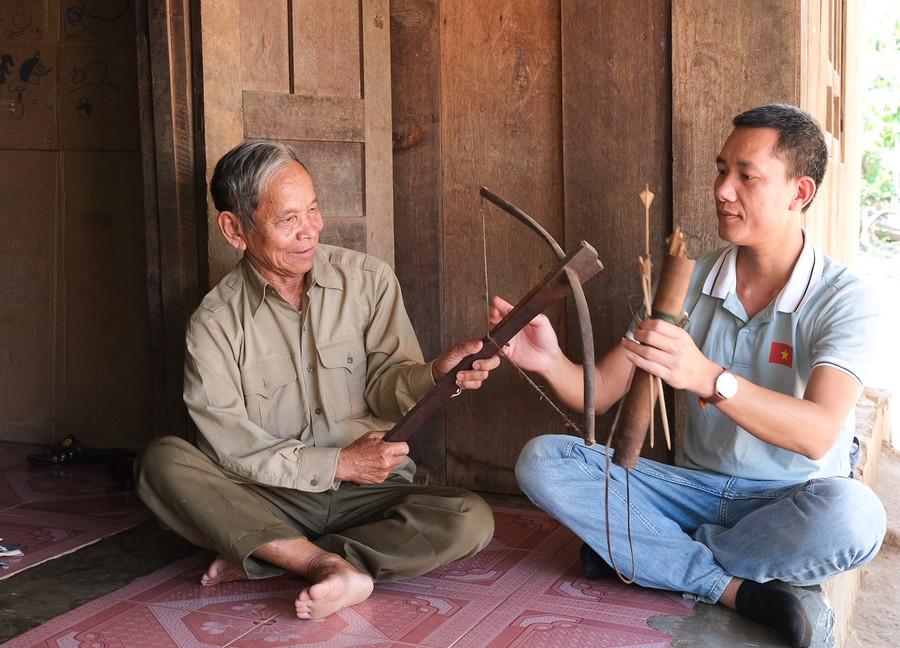 Ông Siu Long (trái) giới thiệu chiếc nỏ ông tự tay làm hơn 30 năm trước. Ảnh: Hoàng Ngọc dscf8643.jpg