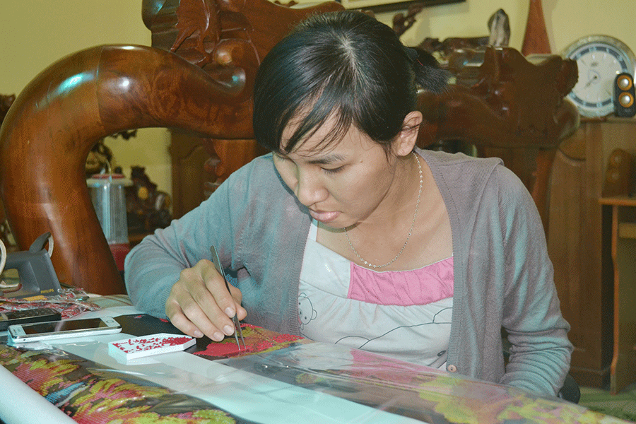 Chị Quỳnh đang hoàn thiện bức tranh gắn đá. Ảnh: Lê Hòa