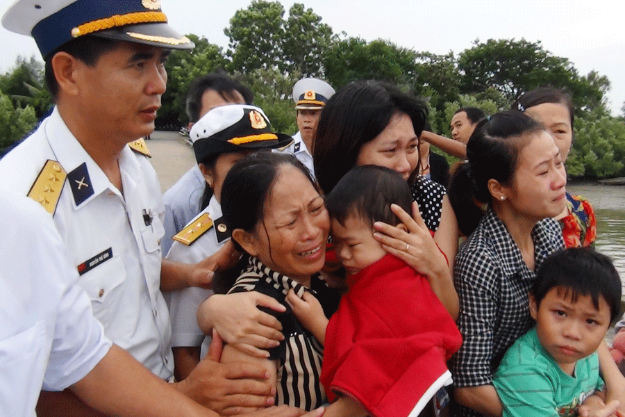 Hai con nhỏ (mặc áo xanh và áo đỏ) trên cầu cảng chờ đón thi thể cha. Ảnh: Mai Thắng 