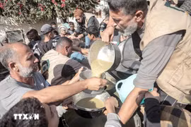 Người dân nhận thực phẩm cứu trợ tại Deir al-Balah, Dải Gaza ngày 23-11. Ảnh: THX/TTXVN