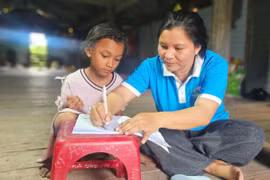 Bà Rơ Ô H’Hieng-Chi hội trưởng Chi hội Phụ nữ buôn Tul (xã Ia Broăi) hướng dẫn em Rơ Ô H’Tra học bài. Ảnh: R.H