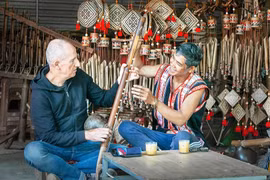 Du khách người Ý thích thú tìm hiểu các nhạc cụ truyền thống Jrai dưới sự hướng dẫn của Nghệ nhân Ưu tú Rơ Châm Tih. Ảnh: Quốc Nguyễn